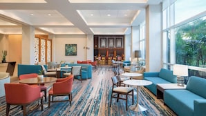Un hall d'hotel amb zones d'estar, un bar i grans finestres que donen vista a l'exterior.