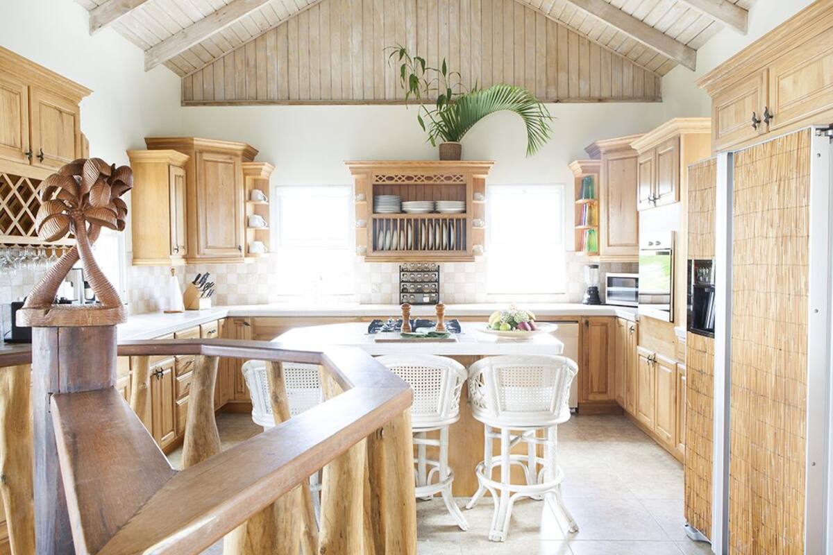 Eine Küche mit Holzausstattung, einer zentralen Kochinsel mit Sitzgelegenheiten und einem Blumentopf.