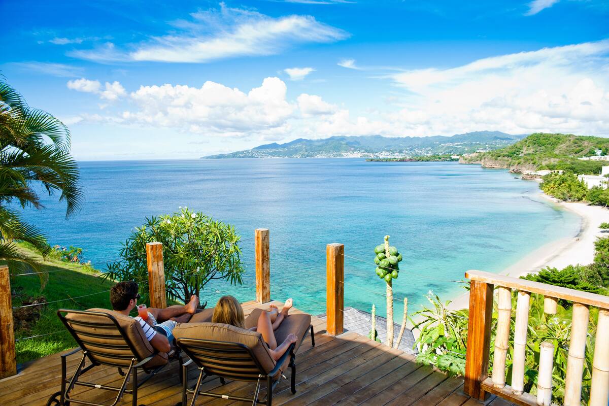 Eine Holterrasse mit Blick auf einen Strand, klares blaues Wasser und entfernte Berge.