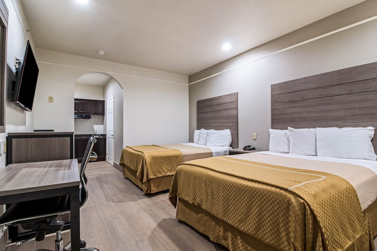 A hotel room with two beds, a desk, and a TV.