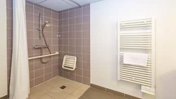 A small, tiled shower room with a showerhead, a towel rack, and a radiator.
