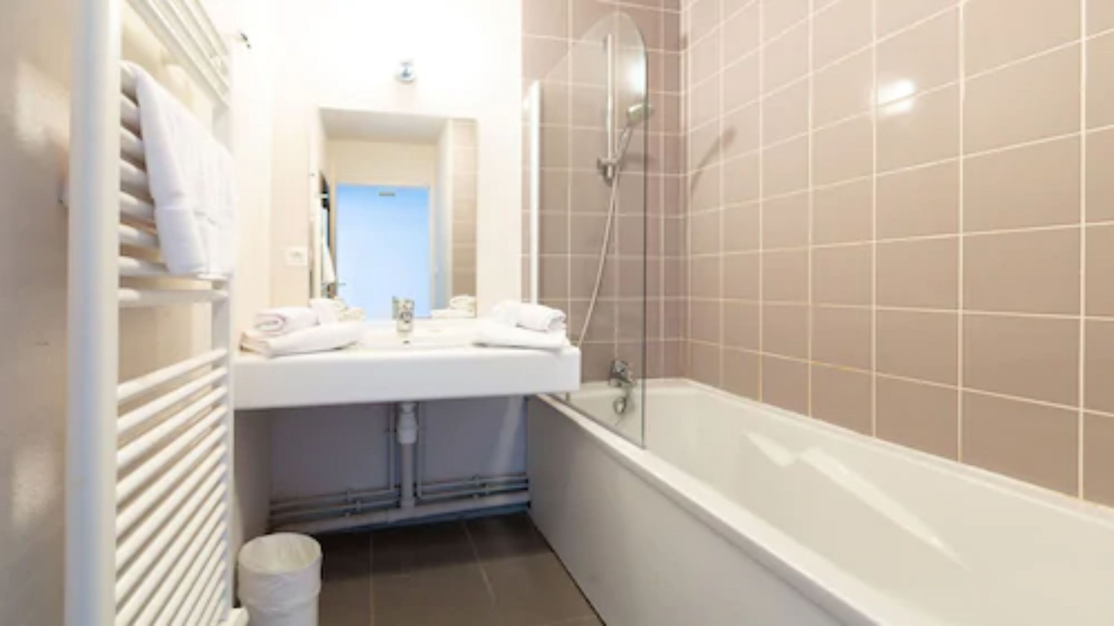 Un baño con lavamanos, espejo y bañera blancos.