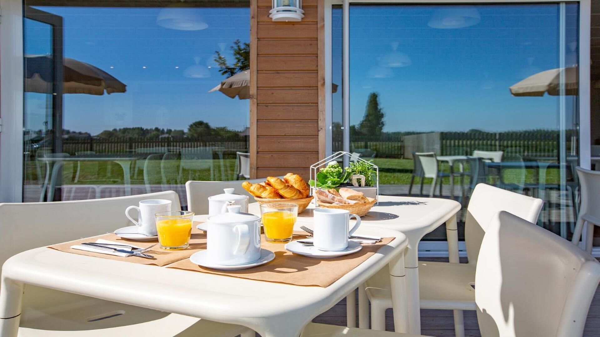 Une table dressée pour le petit-déjeuner, avec des chaises et une vue sur l’extérieur.