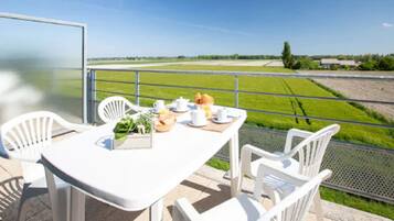 A table set with breakfast items on a balcony overlooking a green field.