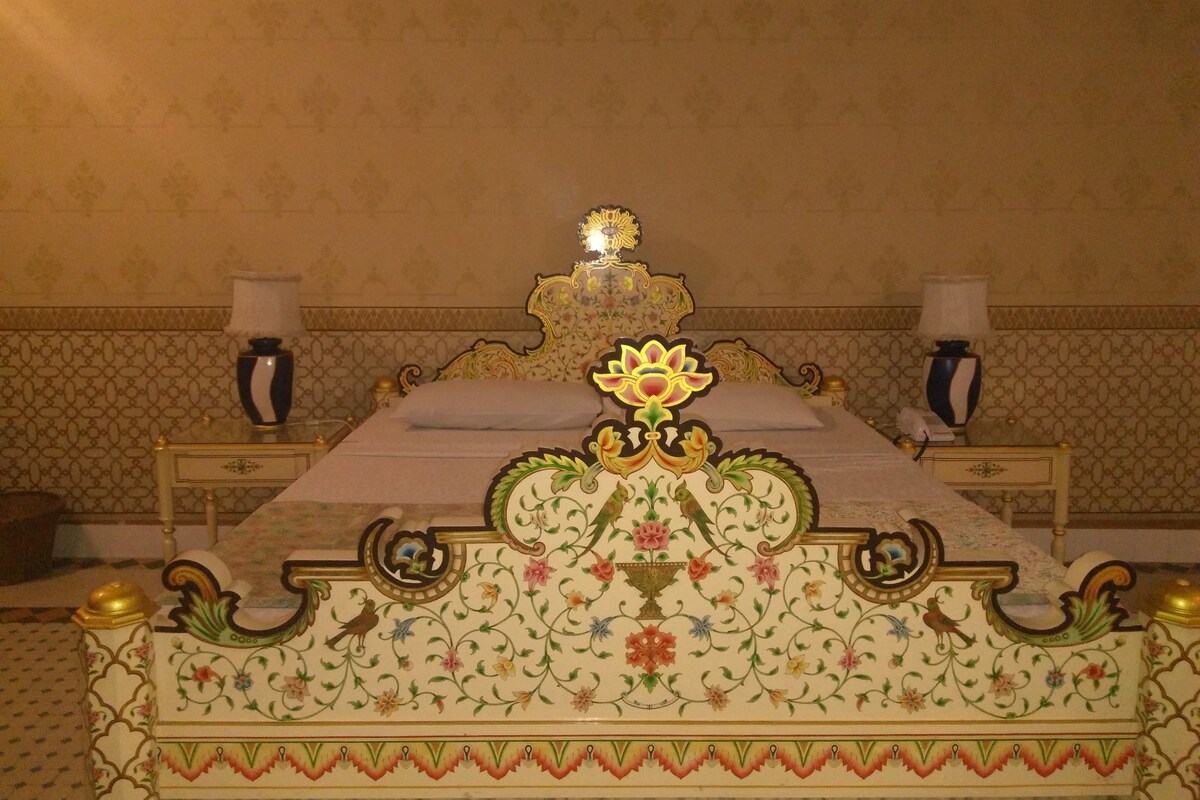 Une chambre avec un lit, deux tables de chevet et un mur orné d’un motif décoratif.