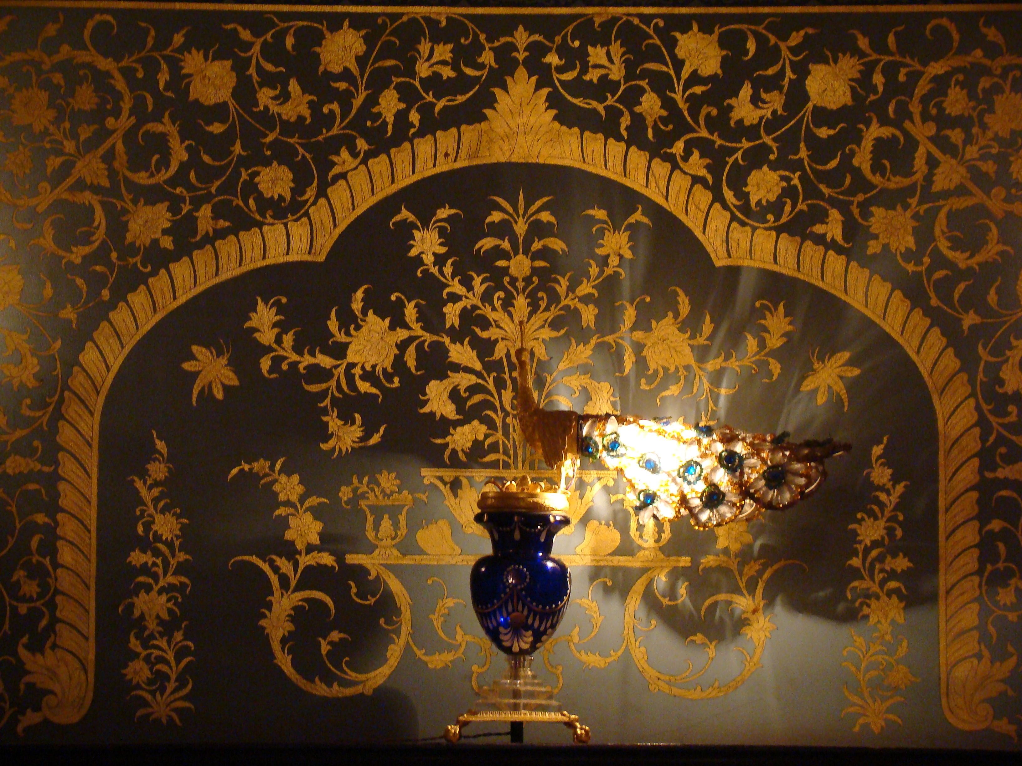 Un soffitto decorato con elaborate decorazioni dorate e un lampadario centrale.