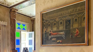 Un salón tradicional con un cuadro grande, un conjunto de sofás y una mesa de centro con libros y objetos decorativos.