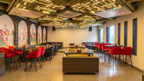 A restaurant with high ceilings, modern lighting, and red chairs. - Treebo Natraj - Jaipur (Jaipur)
