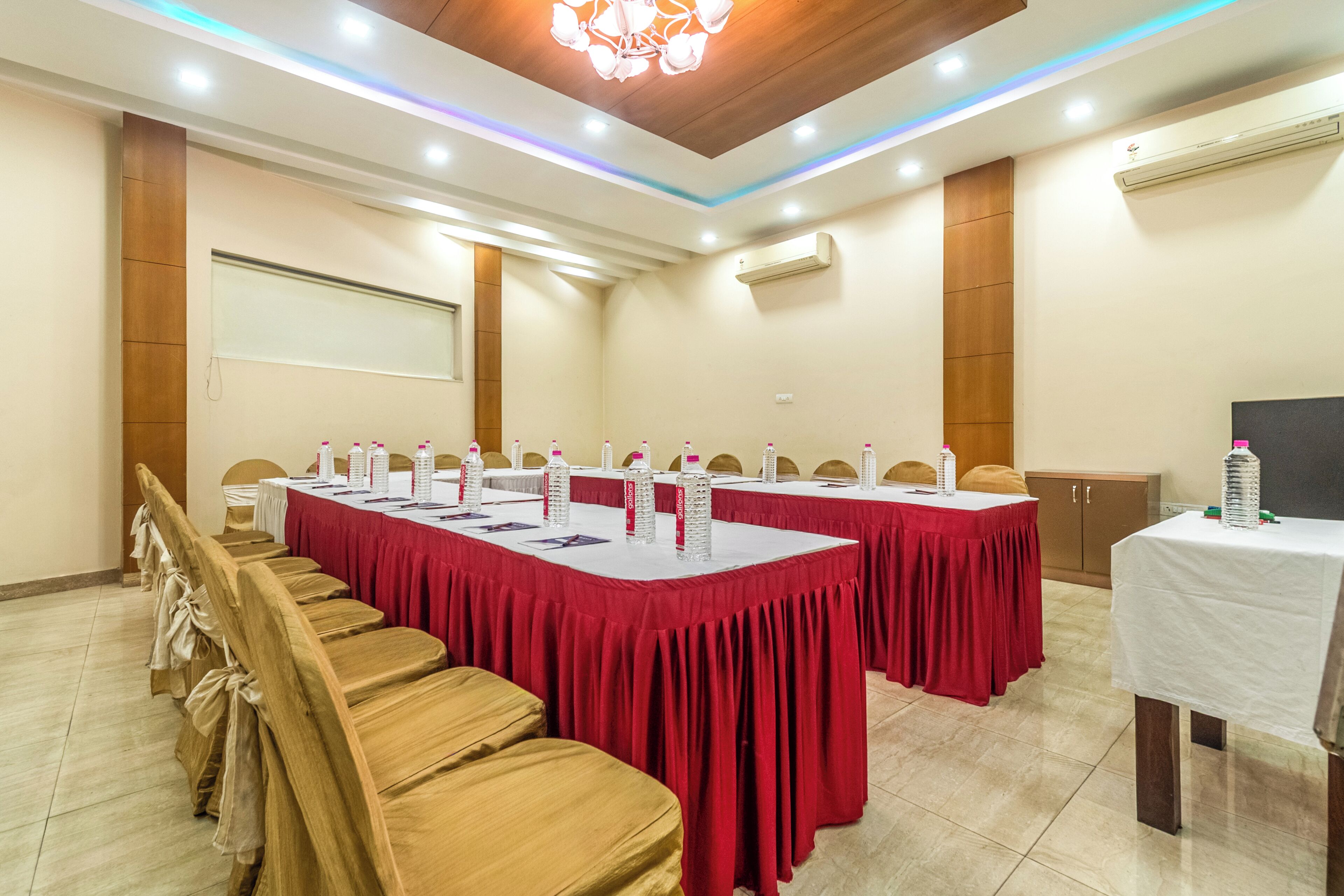 A conference room with long tables, chairs, and a projector screen.