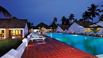 A resort with a swimming pool, lounge chairs, and overwater bungalows.
