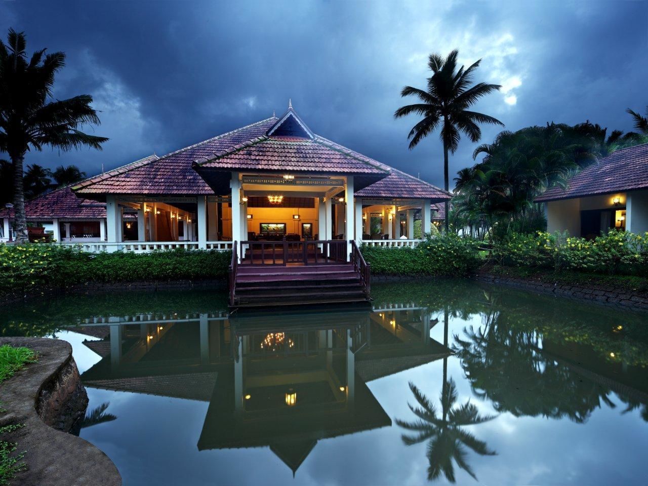 Un resort con una piscina grande, una entrada techada y un entorno tropical.