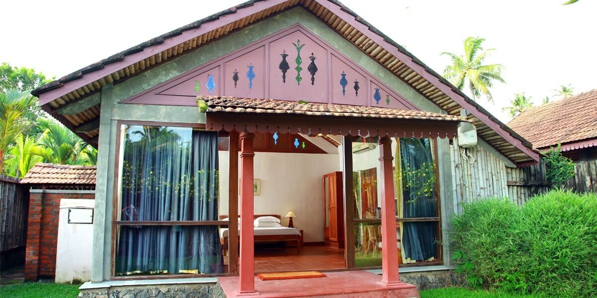 Una casa de un piso con un porche, una cama y una ventana con cortinas.
