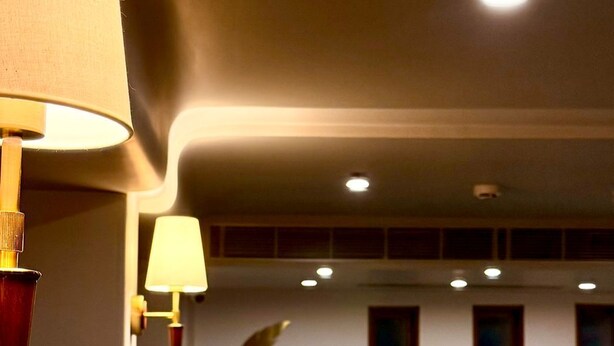 Área de recepção de hotel com o letreiro 'Shilton', um balcão de atendimento e design de interiores moderno.