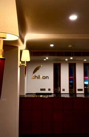 A hotel reception area with a 'Shilton' sign, a reception desk, and a modern interior design. - Shilton International (Kanayannur)