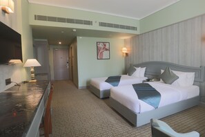 A hotel room with two beds, a desk, and a mirror. - Shilton International (Kanayannur)