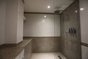 A modern bathroom with a glass shower enclosure, a granite countertop, and a wall-mounted towel rack. - Shilton International (Kanayannur)