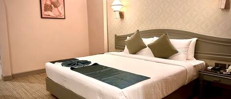 Una habitación de hotel con una cama grande, una mesita de noche con un teléfono y una lámpara de pared.