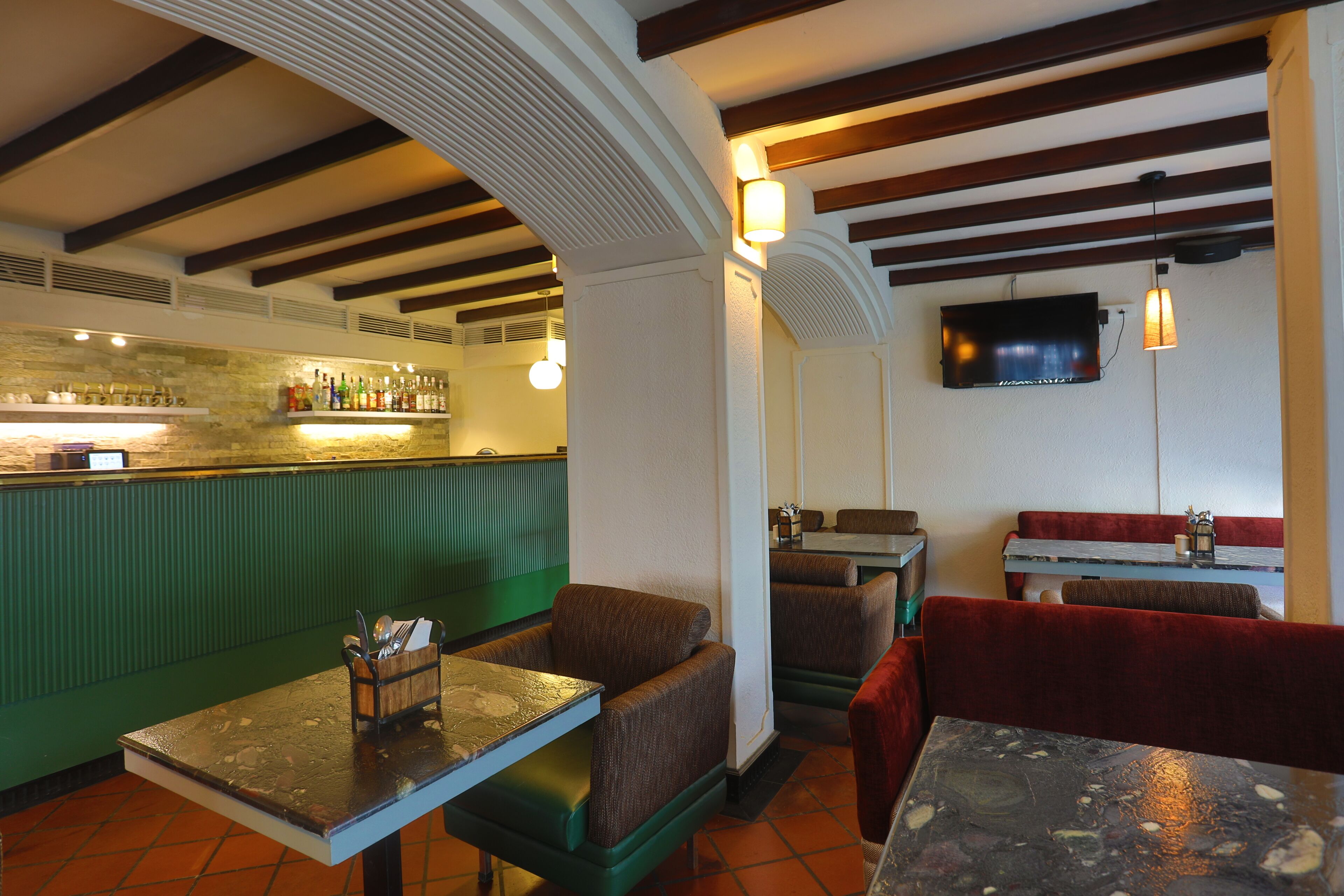L’intérieur d’un restaurant, avec des banquettes, un coin bar et un téléviseur fixé au mur.