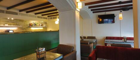 L’intérieur d’un restaurant, avec des banquettes, un coin bar et un téléviseur fixé au mur.