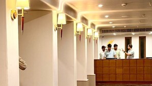 Uma área de recepção de hotel com piso de mármore, balcão de atendimento e áreas de estar.