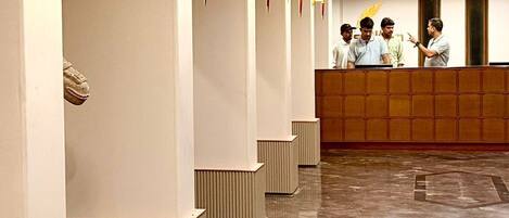 A hotel reception area with a marble floor, a reception desk, and seating areas.