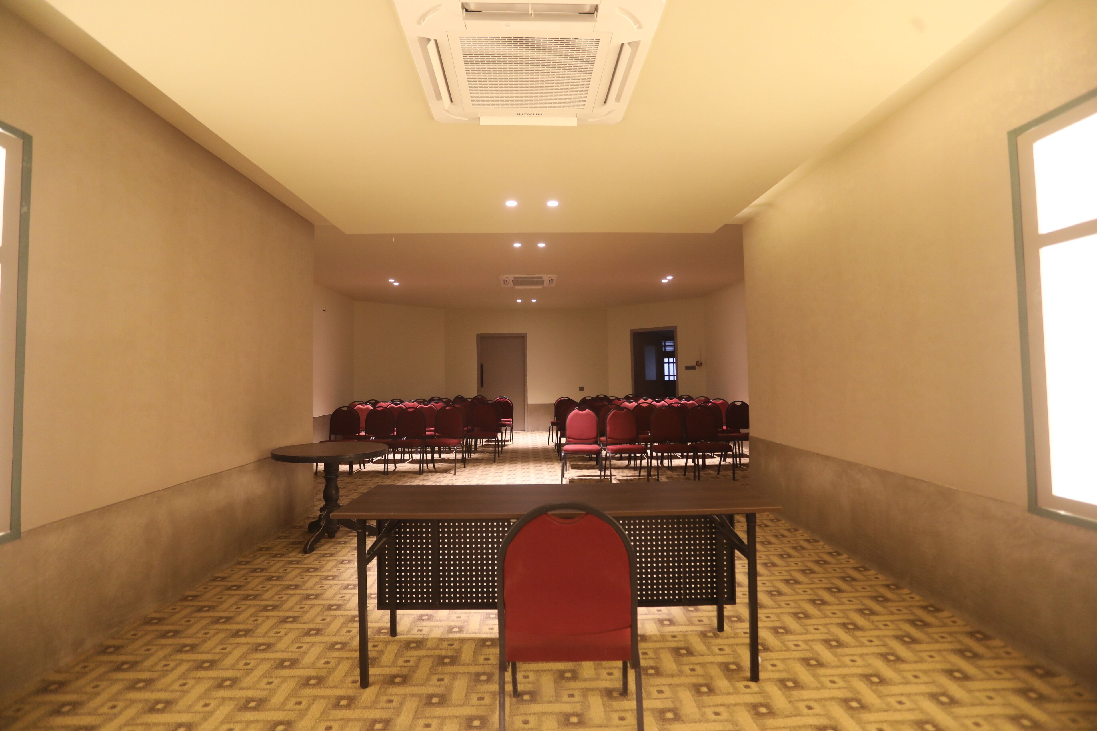 A conference room with a long table, several chairs, and a patterned carpet.