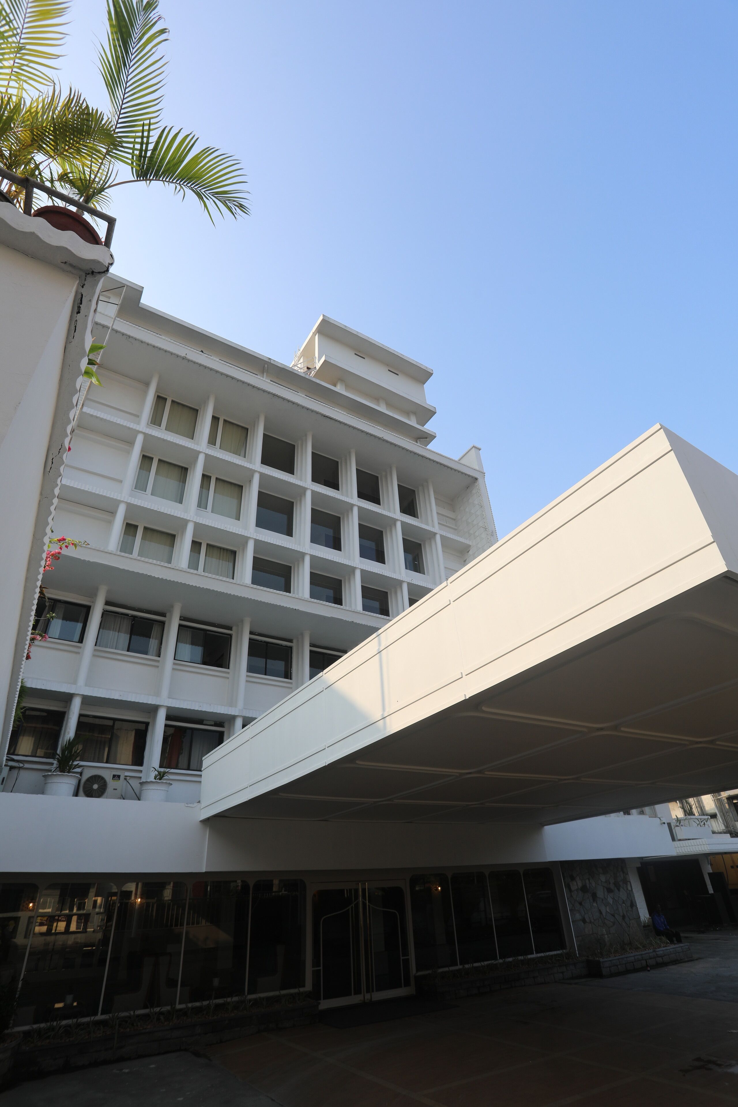 A multi-story building with a flat facade, large windows, and a covered entrance area.