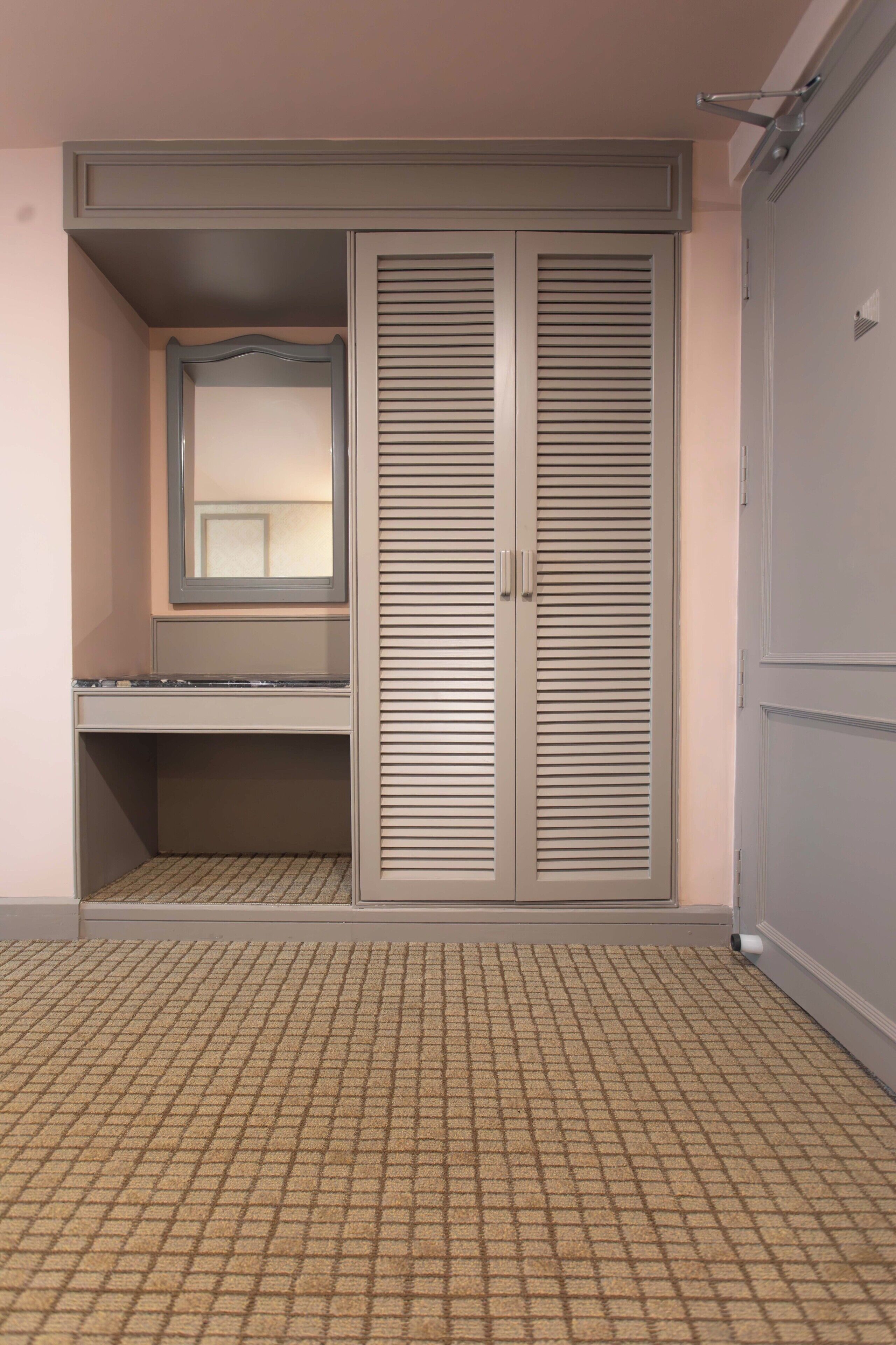 A room with a wardrobe, a mirror, and a shelf.