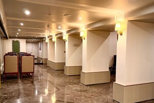 Un vestíbulo de hotel con piso de mármol, filas de asientos e iluminación empotrada en las paredes.