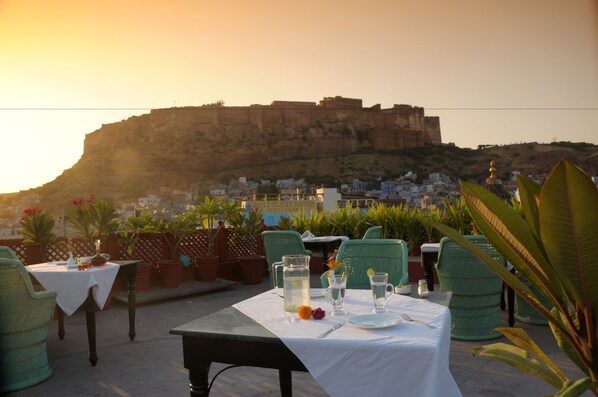 Mesa lista para comer con vista a una fortaleza y edificios al fondo.
