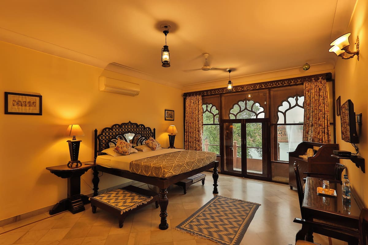 A bedroom with a bed, bedside tables, a desk, and a chair.