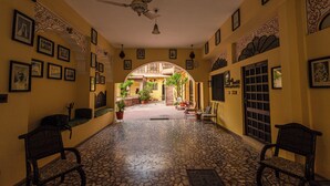 Um corredor com piso estampado, ventiladores no teto e quadros nas paredes.