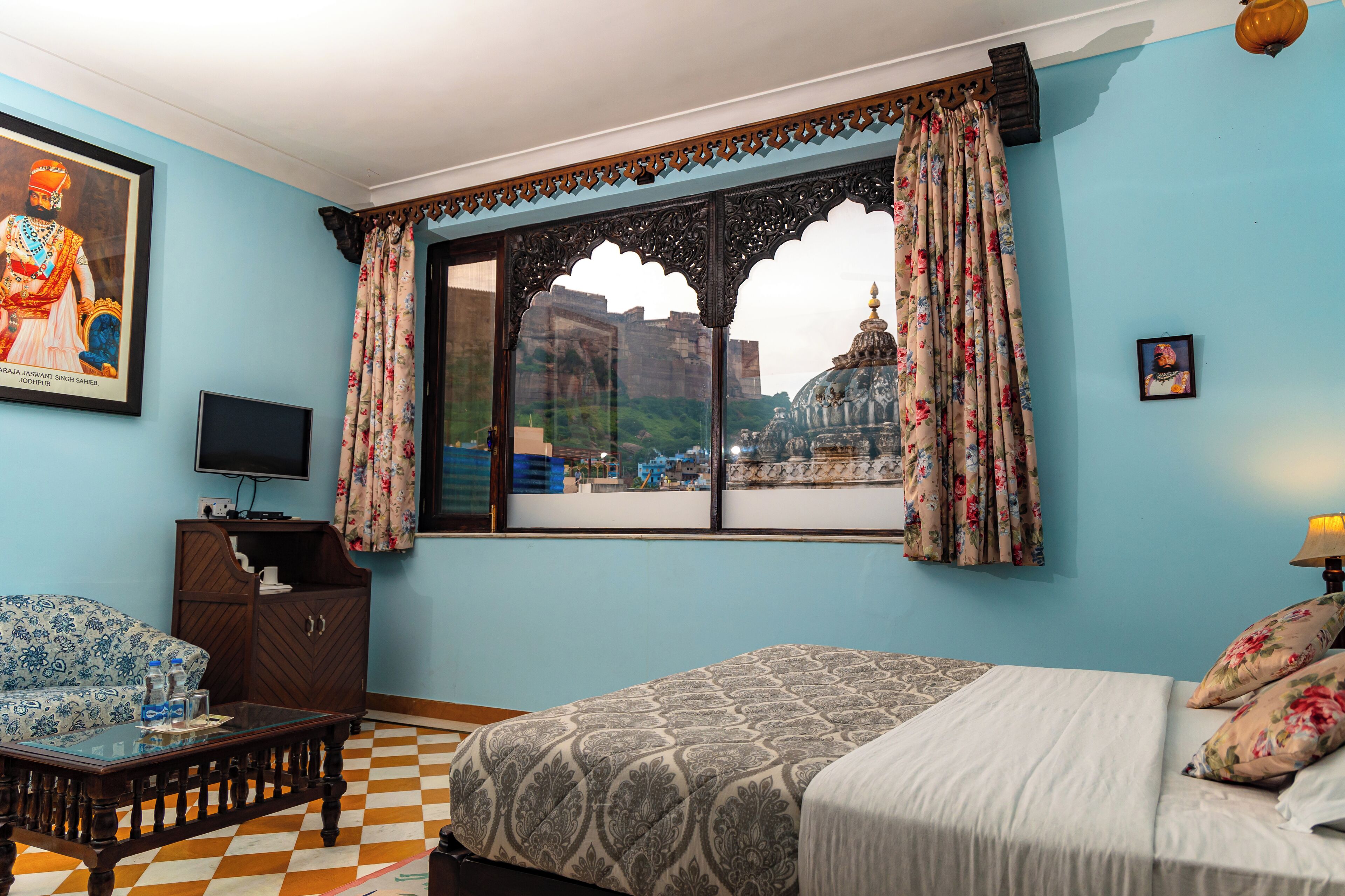 Una habitación con cama, sofá, televisión y ventana con cortinas.