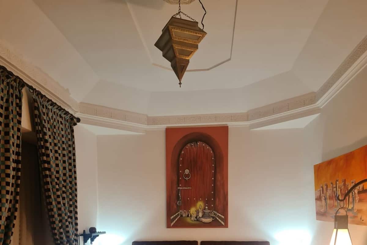 A bedroom with a bed, two bedside lamps, a wall-mounted artwork, and a patterned rug.