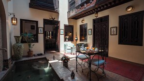 Un patio con piscina, un área de comedor con mesa y sillas, y una escalera que conduce a un nivel superior.
