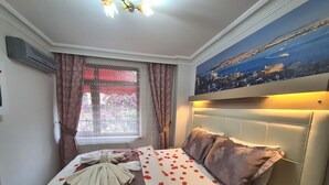 A hotel room with a bed, a window with curtains, a painting on the wall, and an air conditioning unit. - Oceans 7 Hotel  (Istanbul)