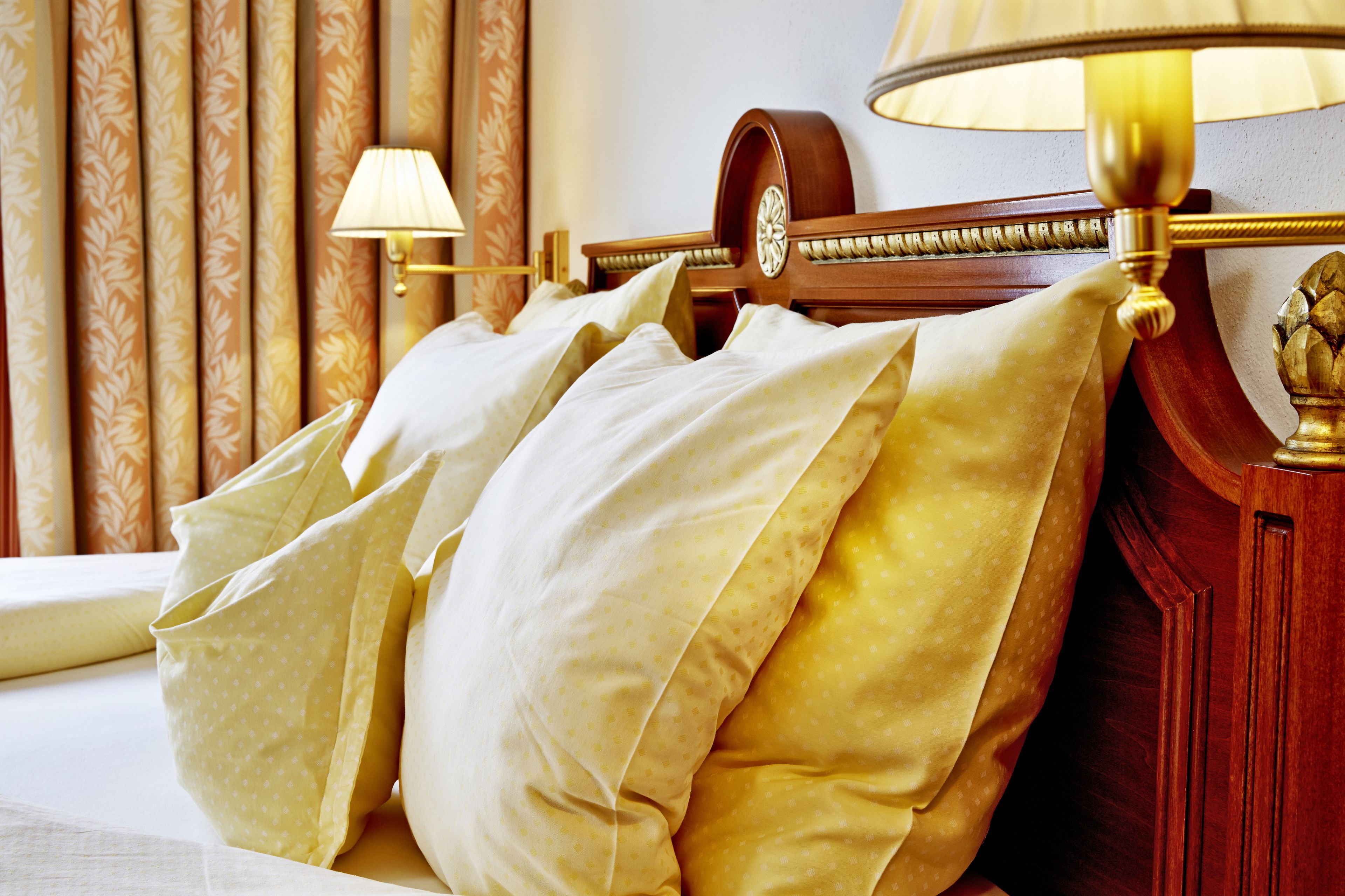 Een bed met meerdere kussens, een houten hoofdbord en een lamp.