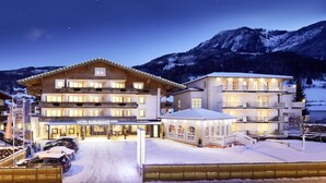 A hotel with multiple floors, a covered outdoor area, and a snowy landscape with mountains in the background. - Hotel Barbarahof Kaprun -  Adults Only (Kaprun)