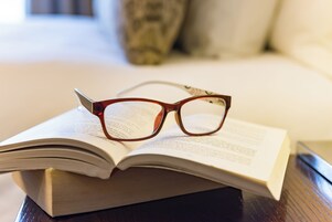 Un libro con gafas encima, sobre una superficie de madera.