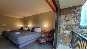 A hotel room with two beds, a massage chair, and a stone wall. - Distinction Mackenzie Country Hotel (Twizel)