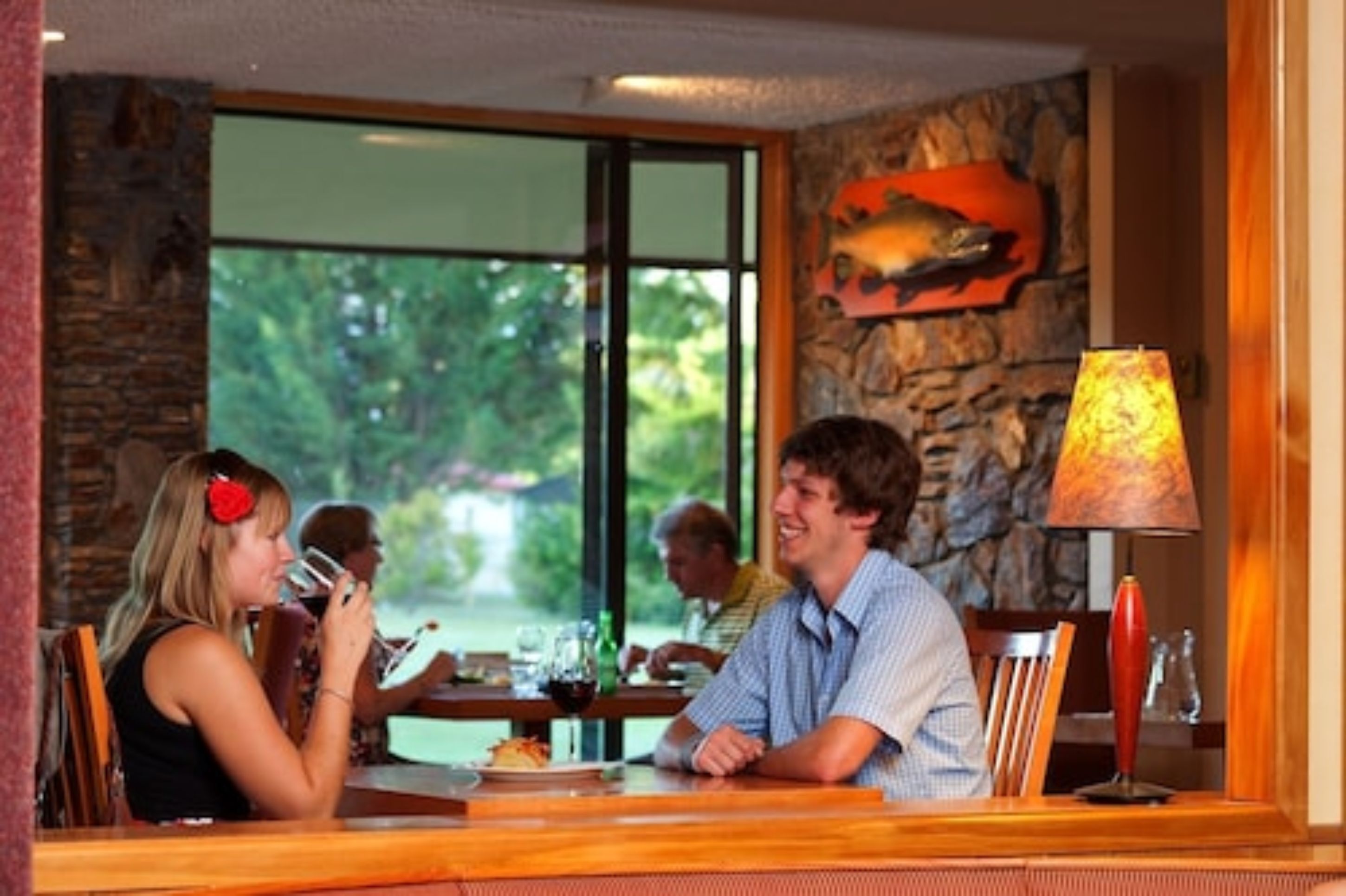 A dining area with a stone wall, a large window, and a table with chairs.