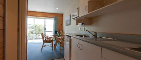 Een moderne keuken met een eethoek, grote ramen en uitzicht op de omgeving.