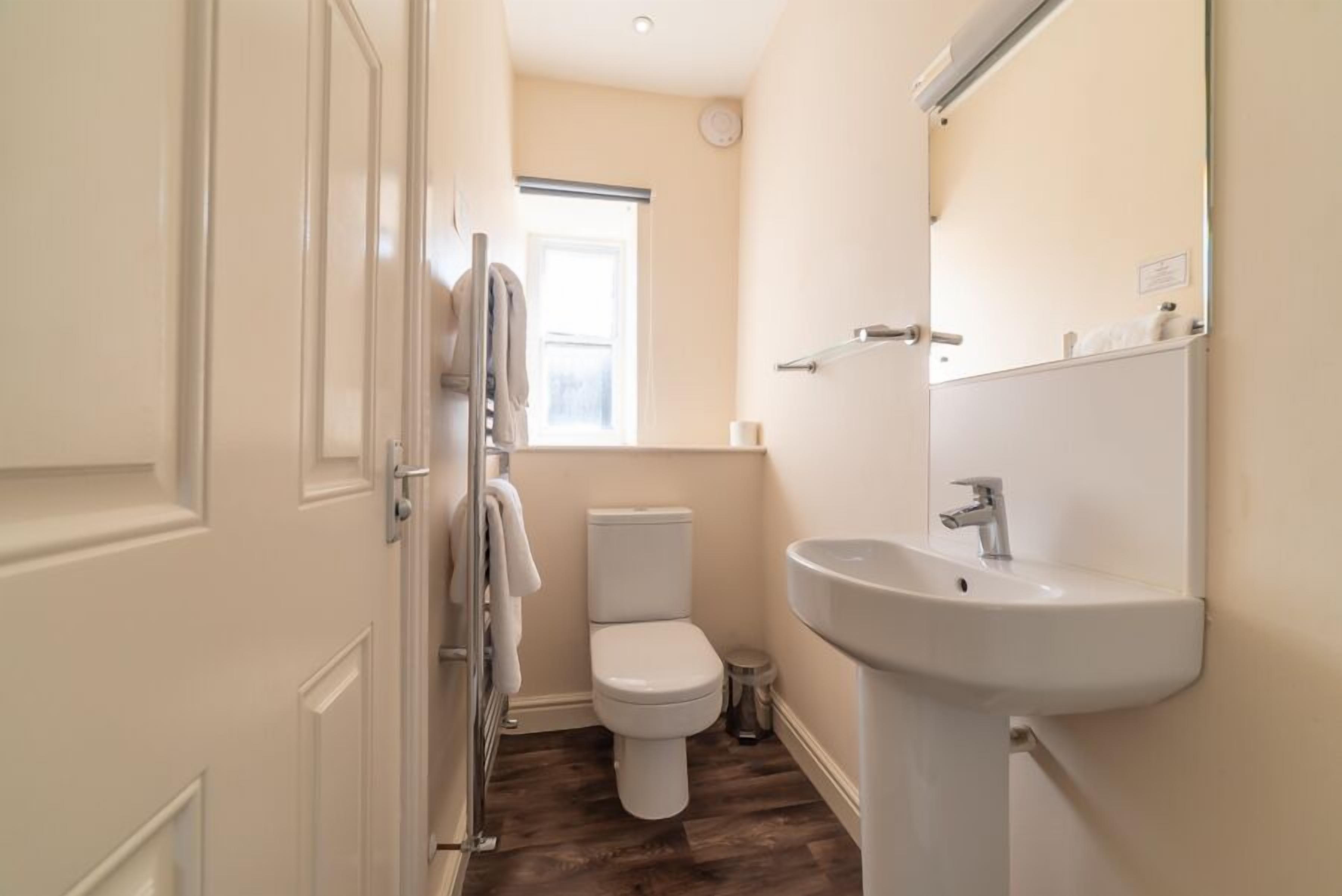 Une salle de bain équipée de toilettes, d’un lavabo et d’un porte-serviettes.