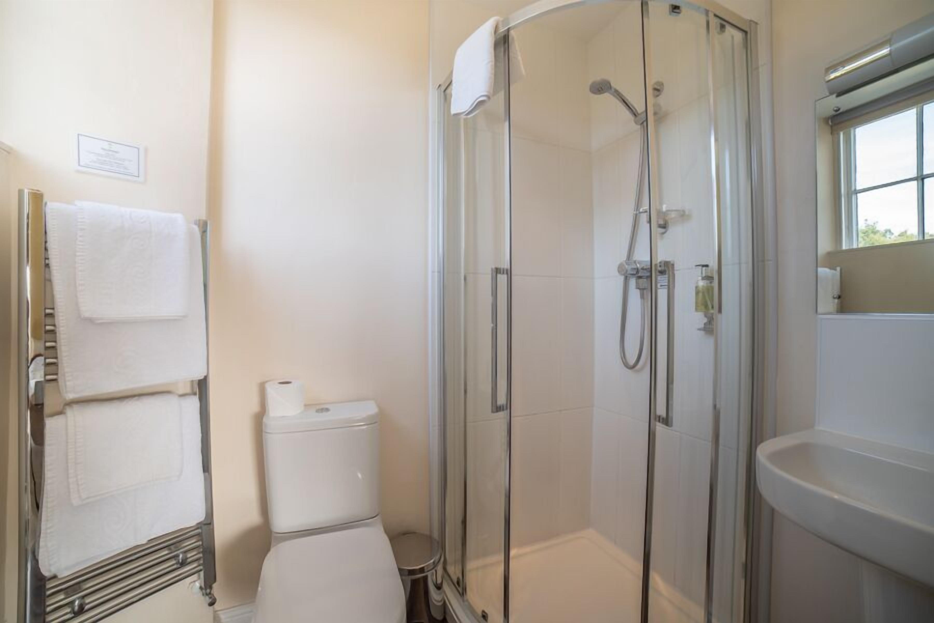 Un baño moderno con ducha de mampara de vidrio, inodoro y lavamanos.