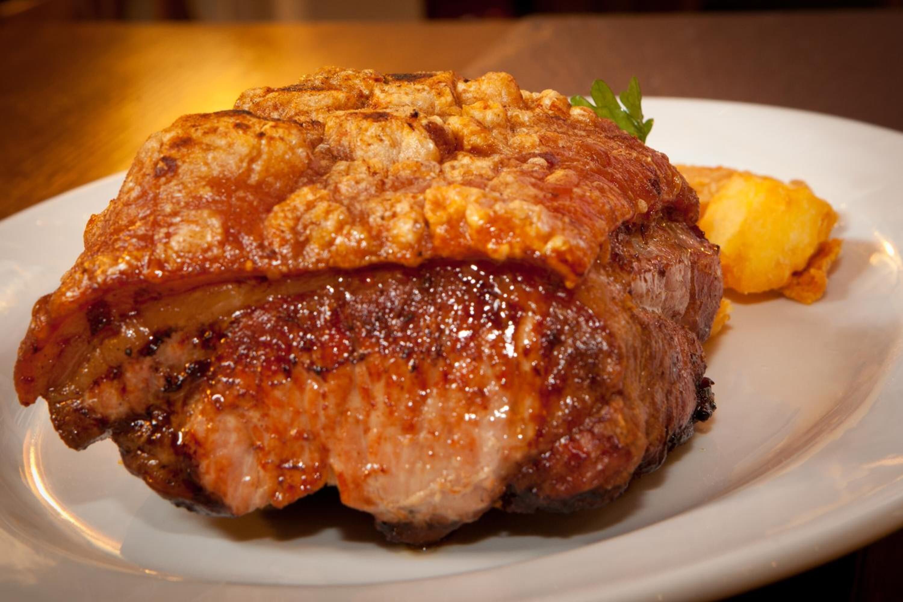 A plate with a grilled meat and a side of potatoes.