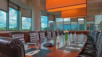 A conference room with leather chairs, a long table, and large windows offering a view of the sky and greenery.