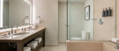 A modern bathroom with a glass-enclosed shower, a large mirror, and a vanity with multiple sinks and a towel rack.