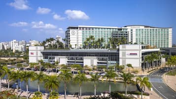 Un hotel Sheraton de diseño moderno, con un amplio aparcamiento y una fuente de agua en primer plano.