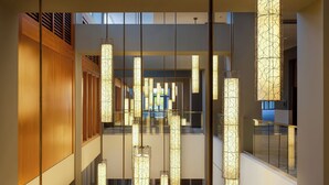 Un intérieur moderne agrémenté de plusieurs luminaires suspendus, d’un mur recouvert de panneaux en bois et d’une rambarde en verre.