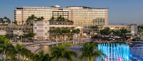 A Sheraton hotel with a large fountain and palm trees in the foreground.